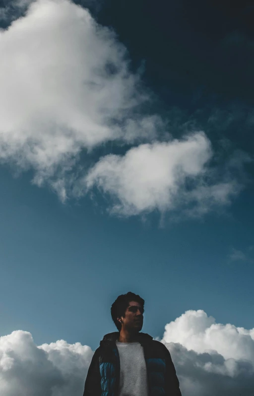 there is a man standing under a very cloudy sky