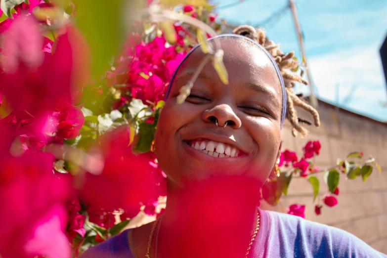 a woman smiling and surrounded by pink flowers