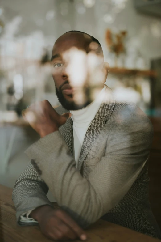 a man with a beard wearing a grey suit and sitting down in a restaurant