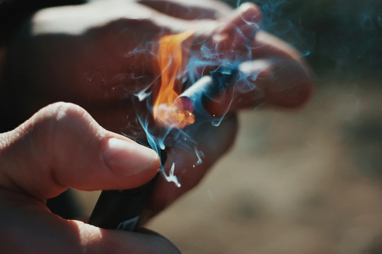 a person holding a smoking lighter in their hand