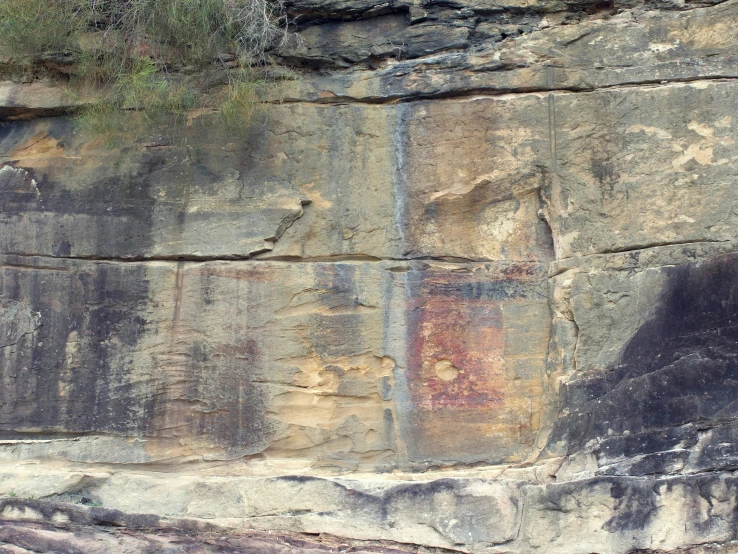 a cliff face with colorful painted faces and grass on the top