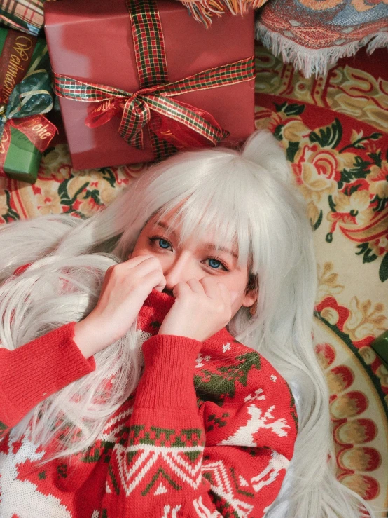 a girl with white hair laying on top of a christmas blanket