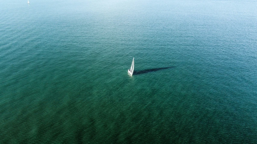 a lone sailboat floats near the surface of the water