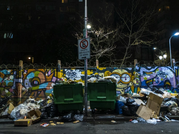 a street with garbage on the ground and graffiti on the wall behind it