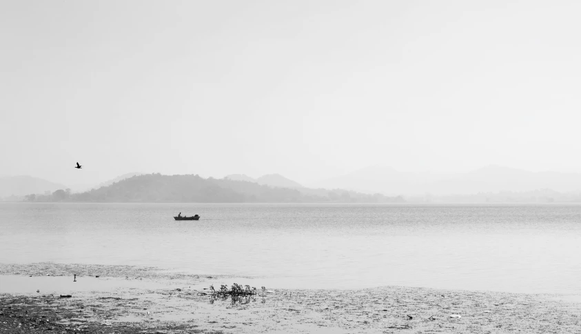 a boat floating in the middle of a lake surrounded by hills