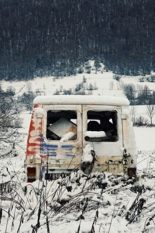 a van covered in snow sitting in the middle of nowhere