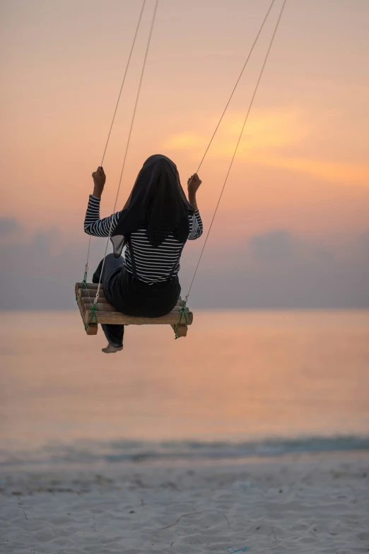 the woman is flying on the rope over the ocean