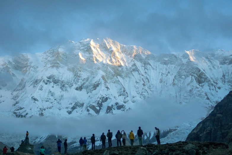 a bunch of people stand in front of a large snowy mountain