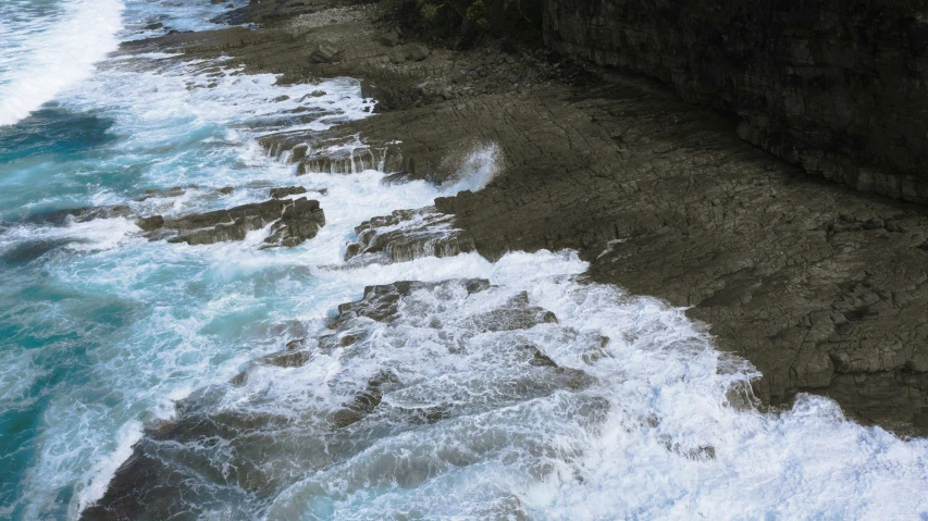 a bird sitting on a cliff over some rough waves