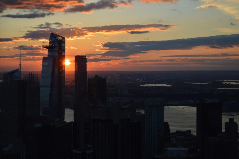 the sun setting in a city, above some tall buildings