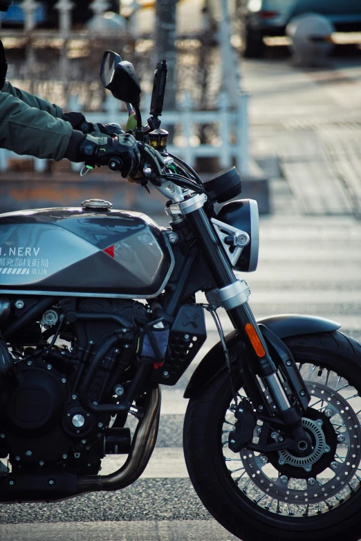 man riding black motorcycle on urban street with cars behind him