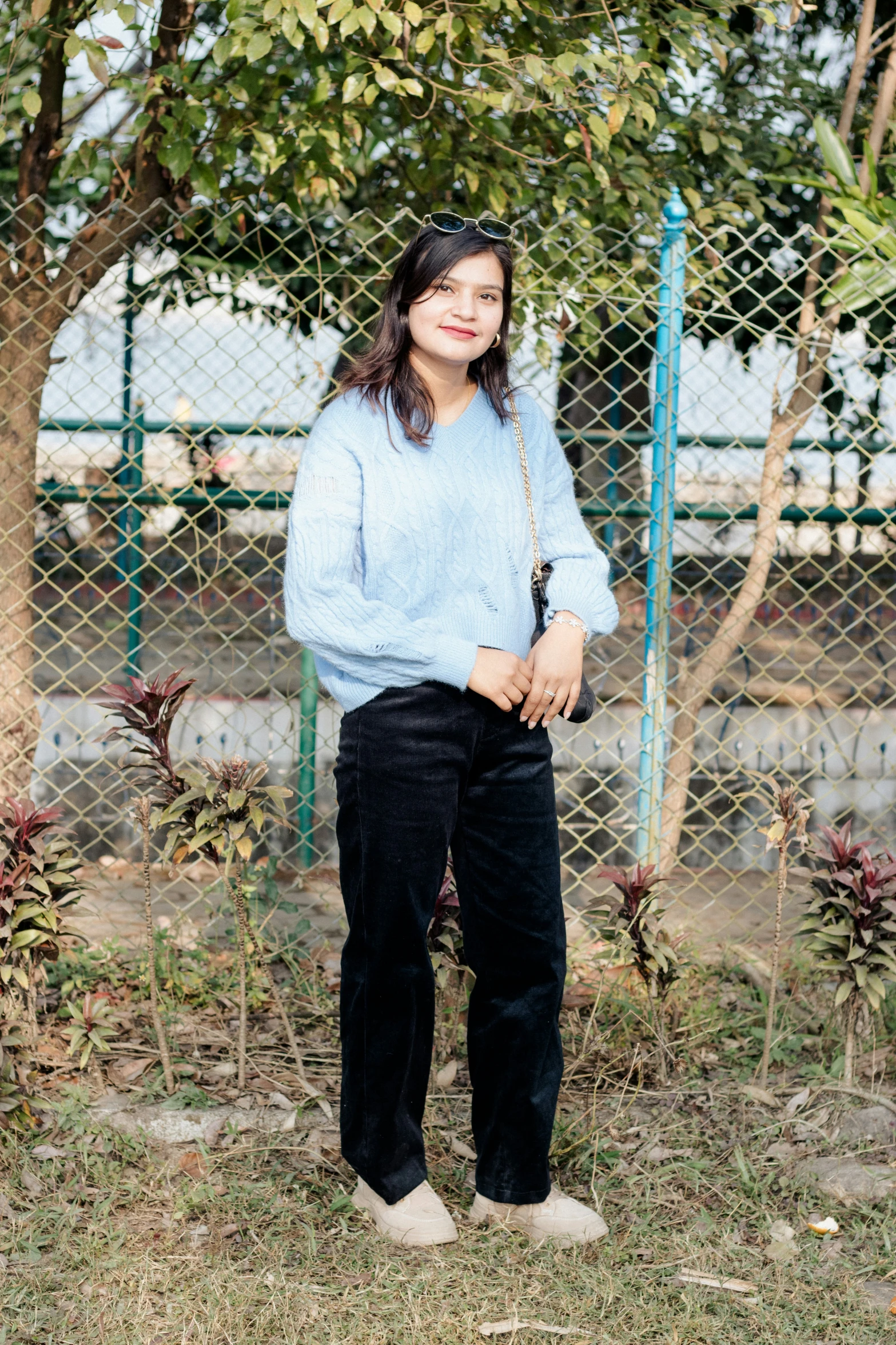 a woman standing in front of a chain link fence