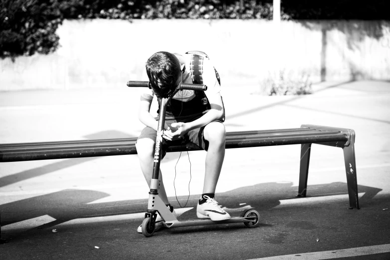 the  is sitting on his scooter with his head bowed and hands crossed