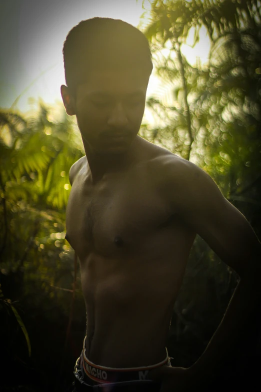 a man that is without a shirt in front of trees