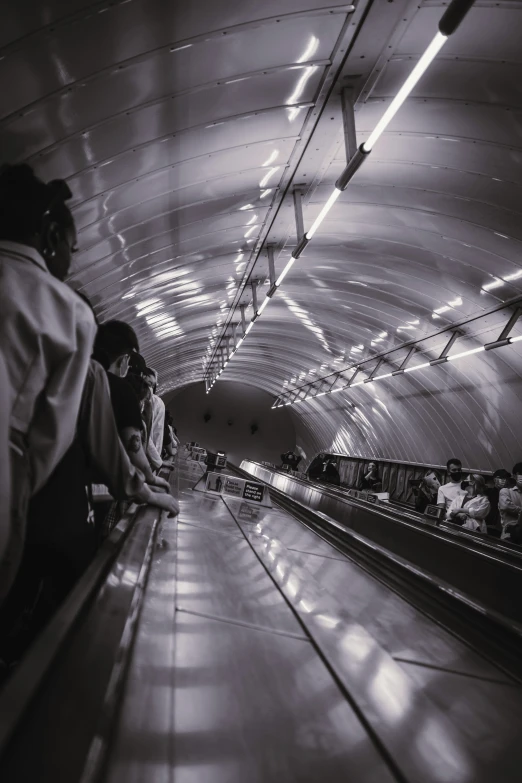 a group of people riding on an escalator next to a long hallway