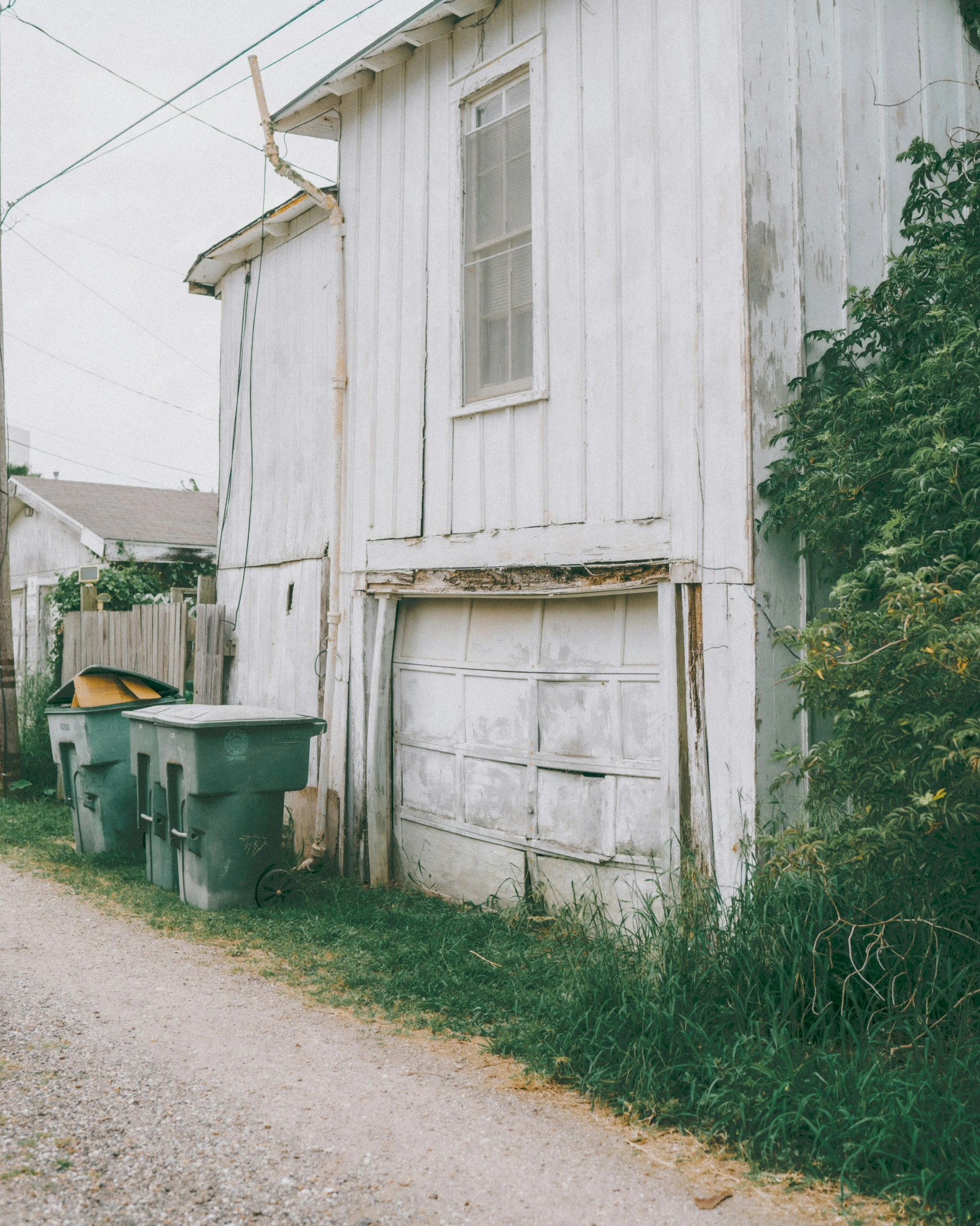 an old white building is shown next to the road