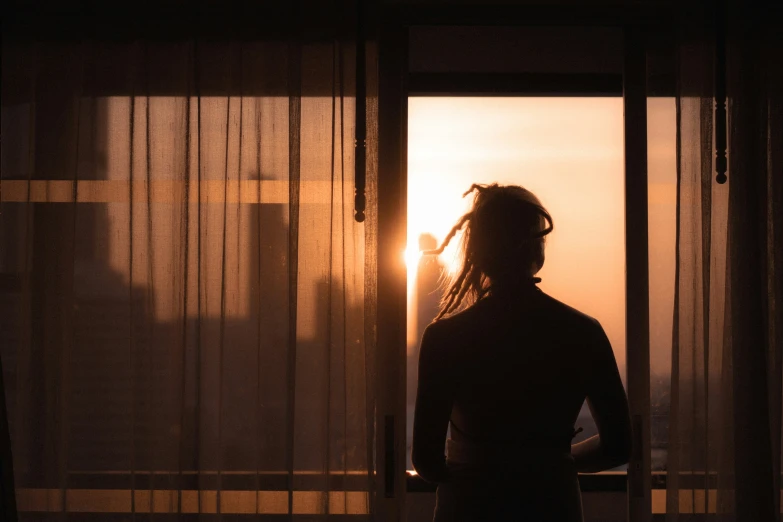 a person standing in front of a window with the sun coming through