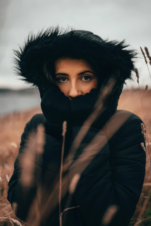 woman in black jacket sitting on grassy field looking at camera