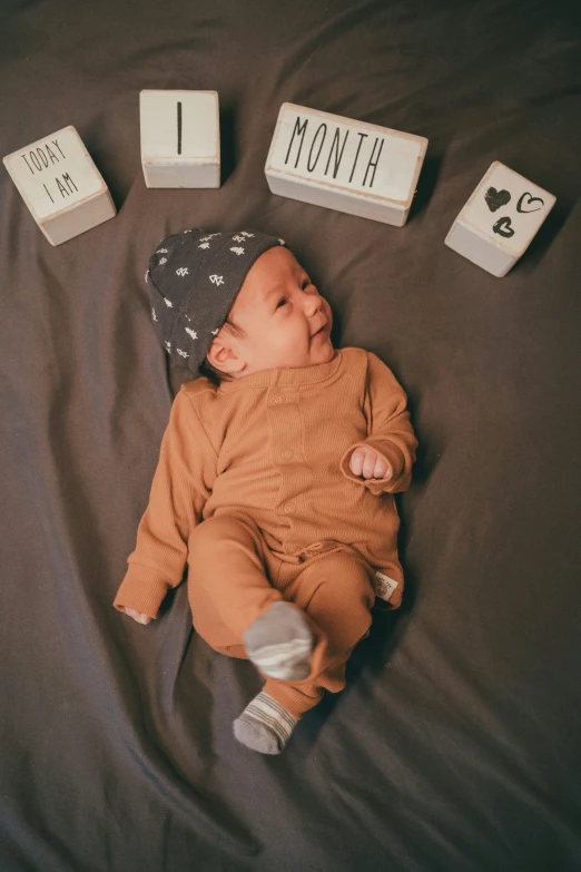 an infant baby has a book set with blocks spelling months