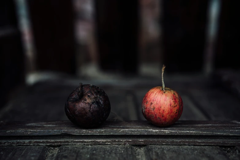 two rotten apples sitting on a wood floor