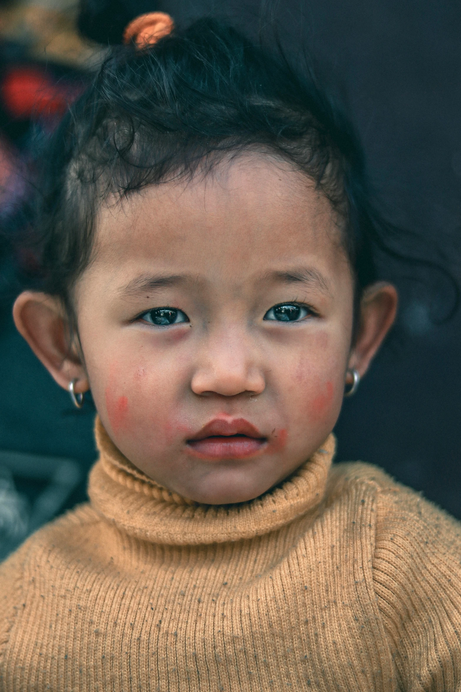 an asian baby looks straight ahead while staring into the camera