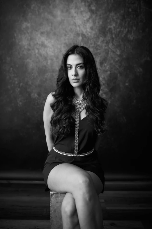 woman in dress and boots sitting on concrete