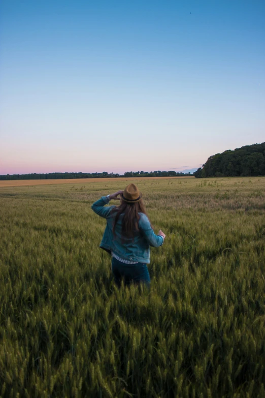 a girl in a large open field with her back to the camera