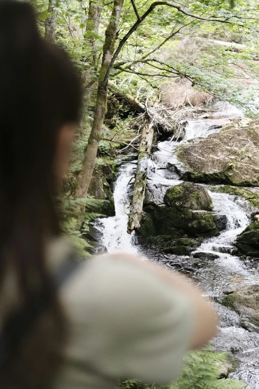 a woman is standing next to a water fall