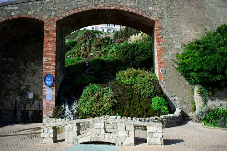 a stone wall with an arch over it in a park