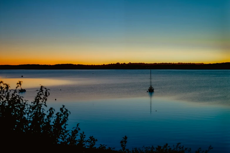 small boats floating on a lake during the sun rise