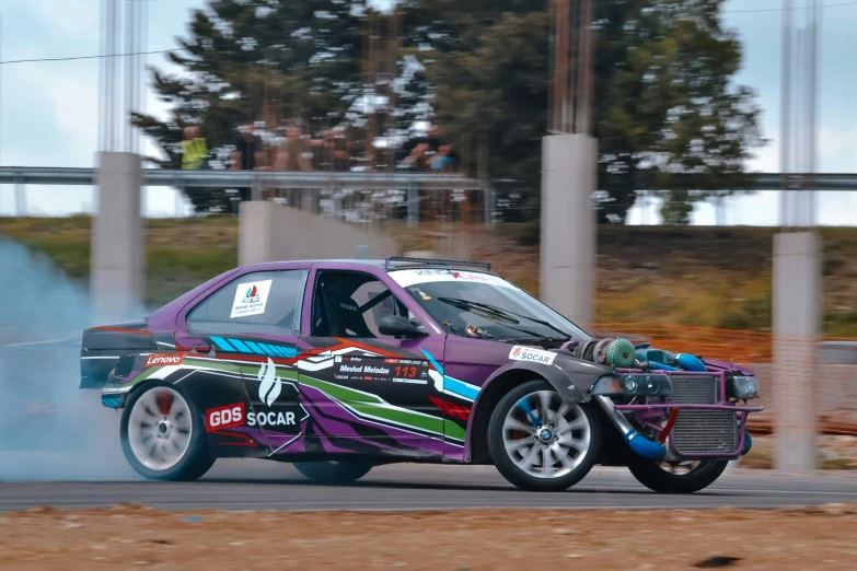 a small car with its hood down driving through a track