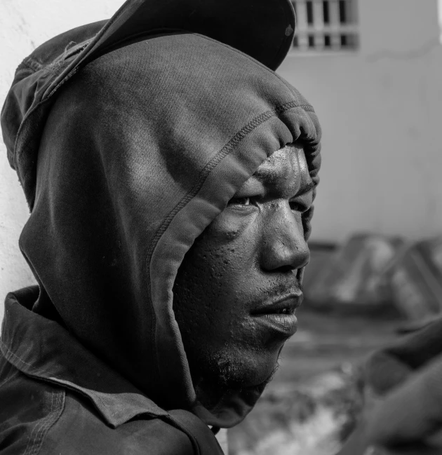 a man in a black cap and sweatshirt and a face covered with a knitted hood