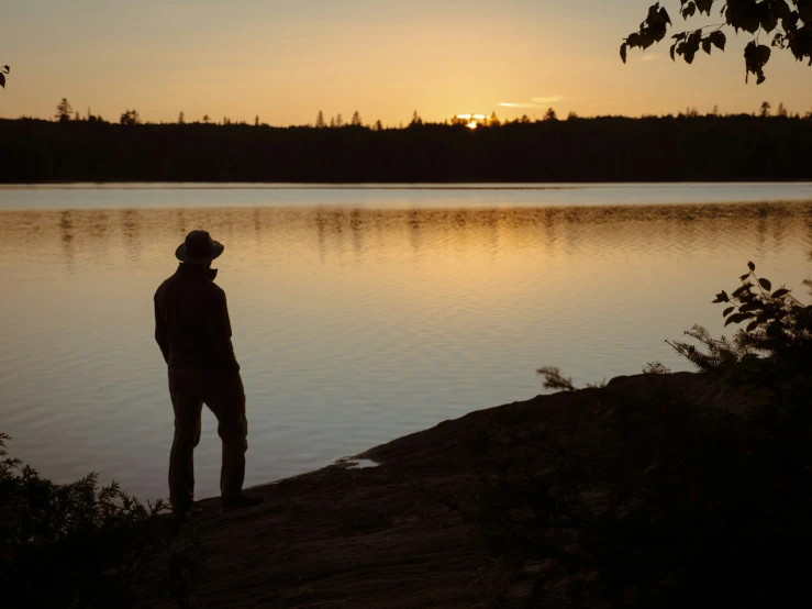 a man standing on the shore watching sunset