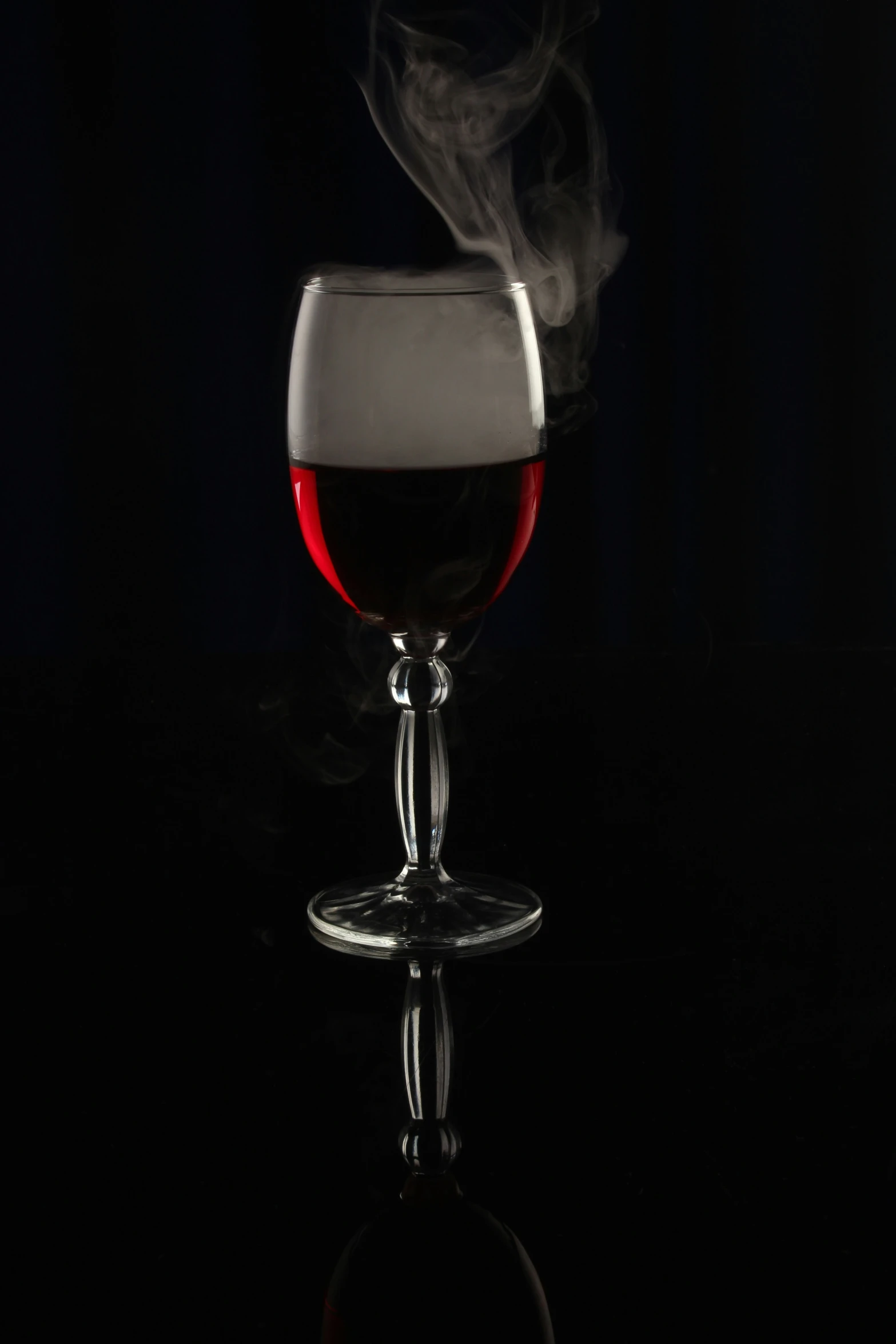 a steaming wine glass with red liquid on a dark table