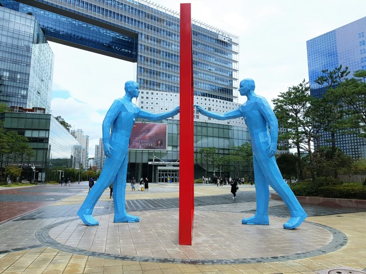 two blue statues near each other with buildings in the background