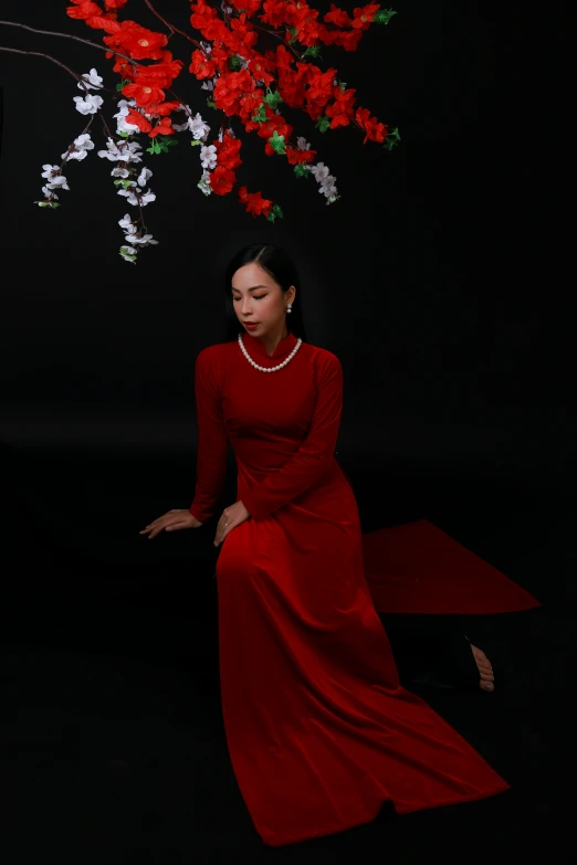 a woman in a red dress sitting under a tree