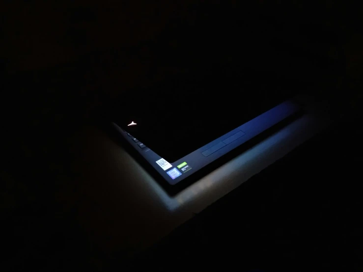 a laptop computer glowing in the dark with the bottom of it on display