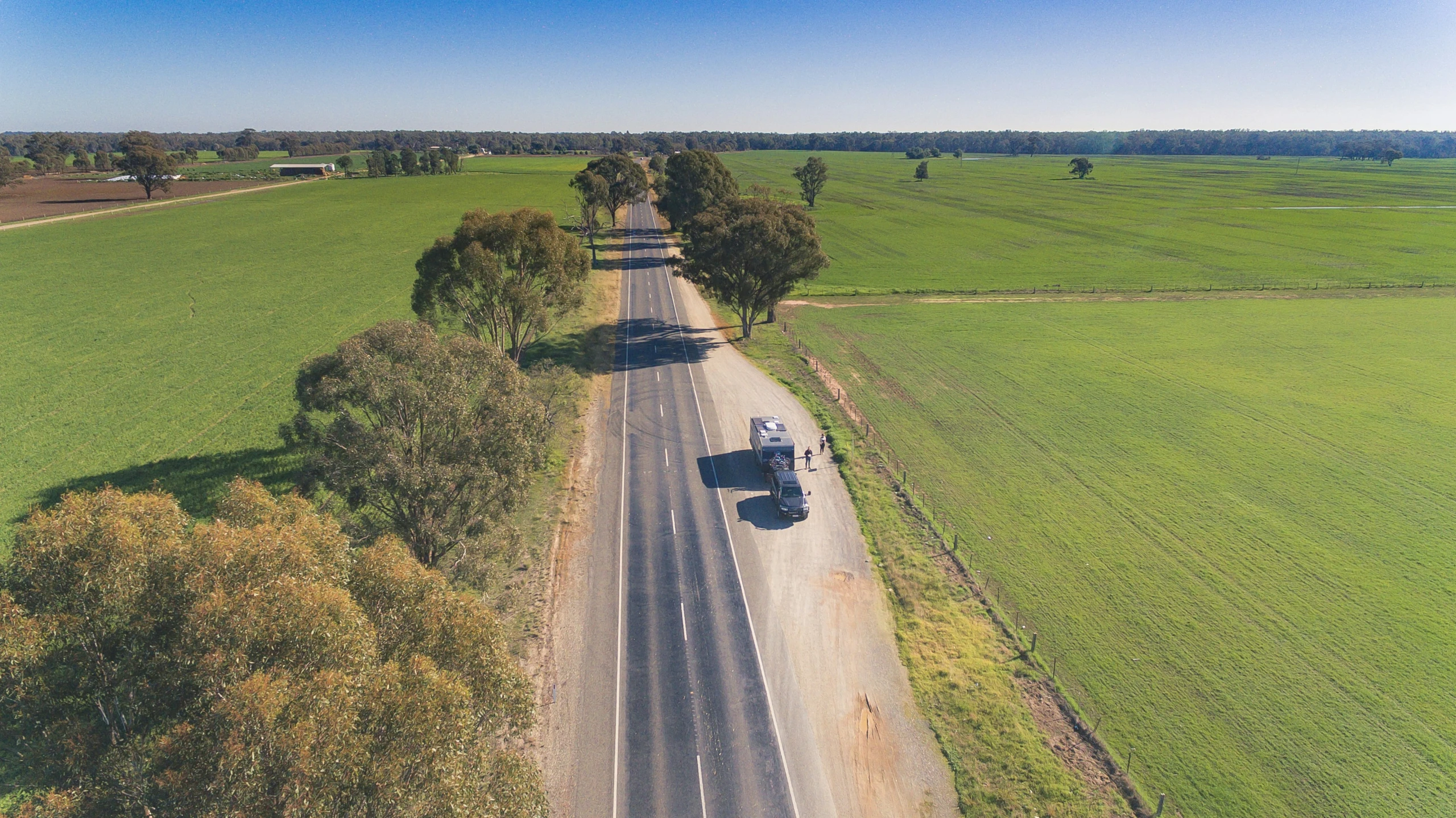 an aerial view of cars driving on a long, dirt road