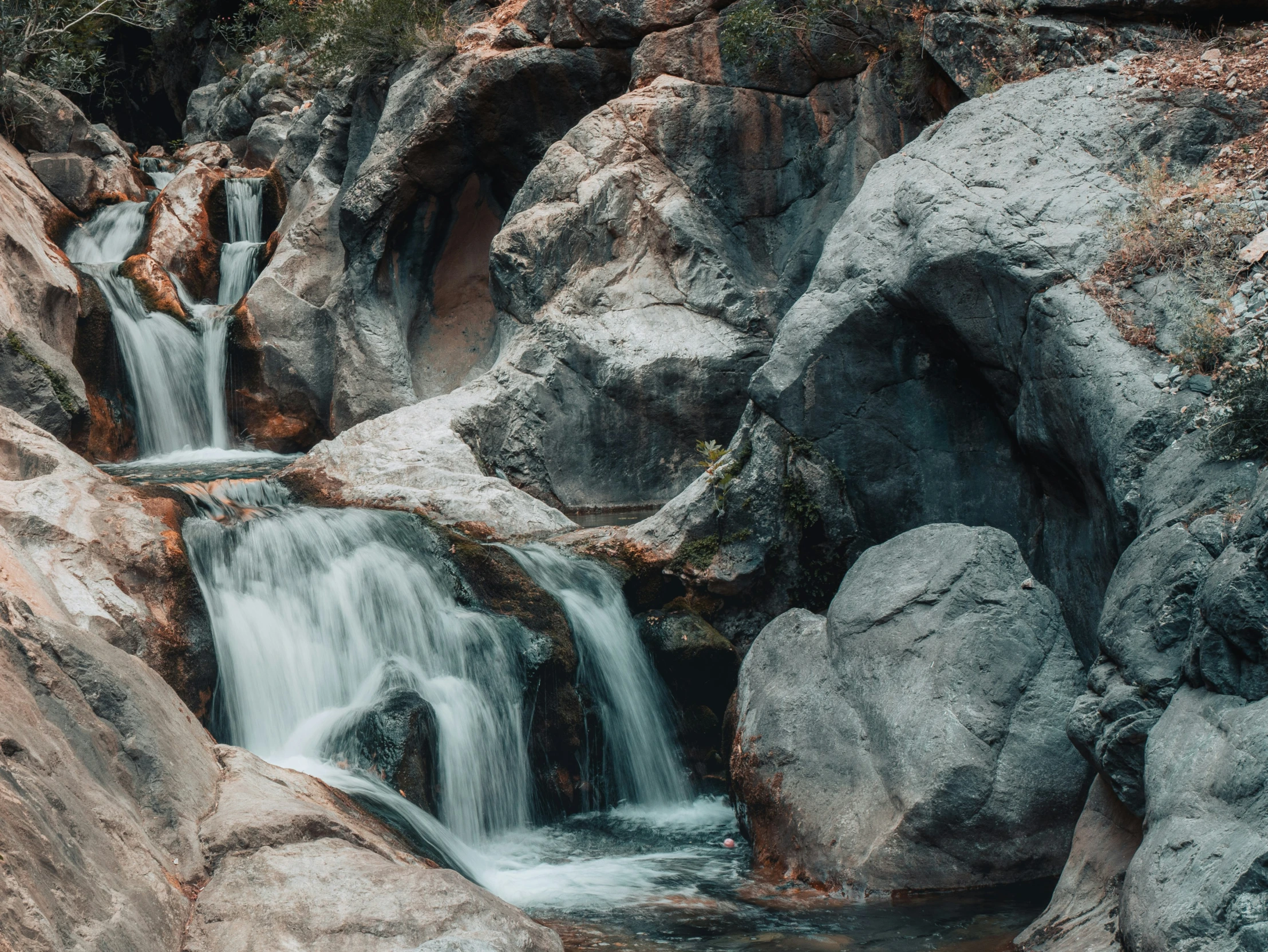 a stream of water flows between some large rocks