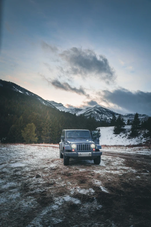 a jeep is driving in an open field at sunset