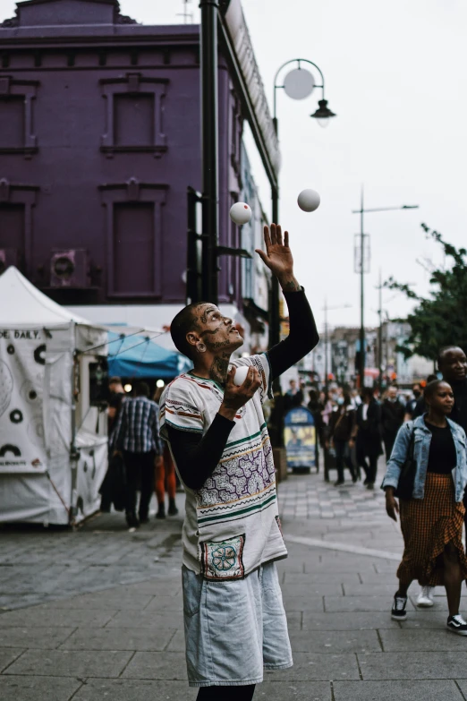 a man is throwing balls on a city street