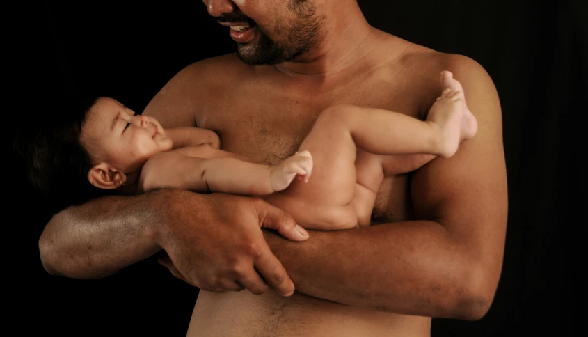 a man holds his  baby while smiling