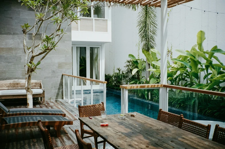 an outdoor dining table sits on the balcony near a pool