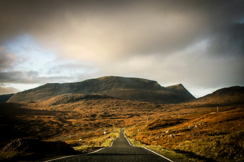 an empty road leading to a mountain range