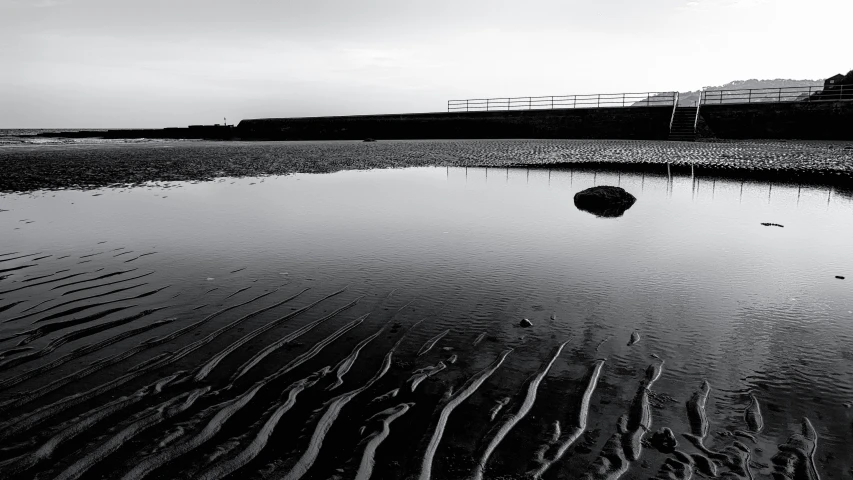 a reflection of an umbrella in water at the beach