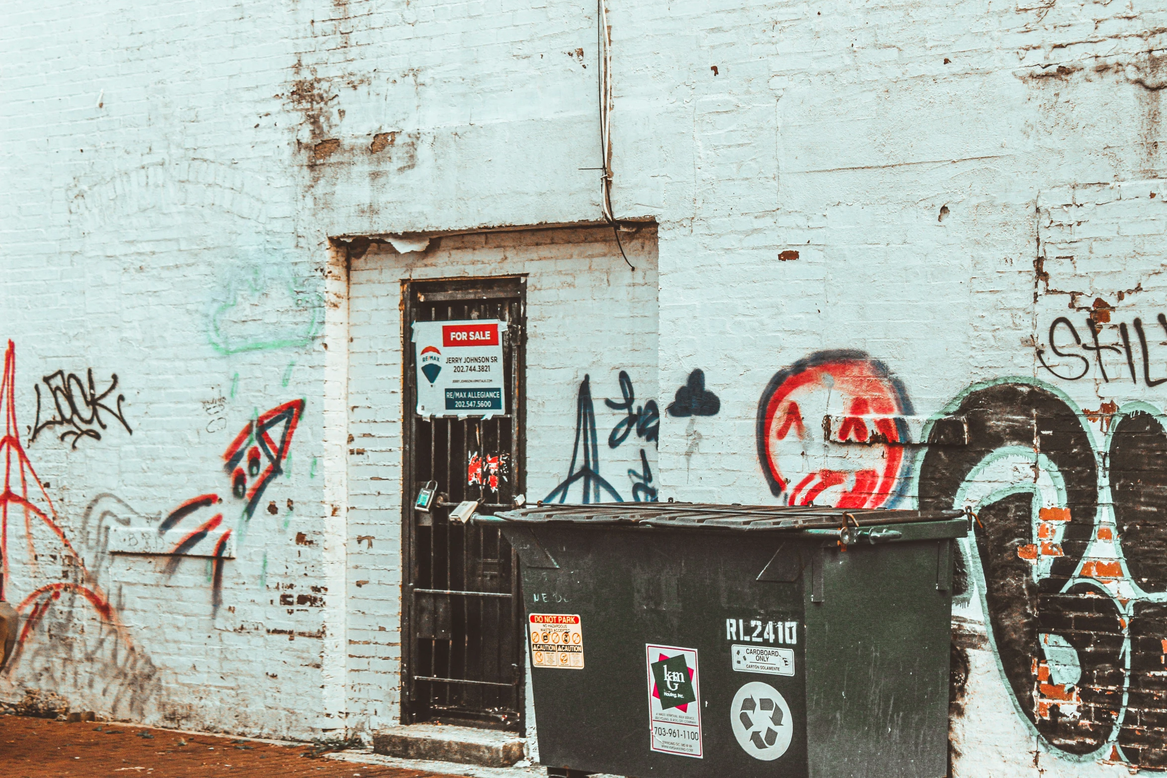 a white brick building has some graffiti on the walls