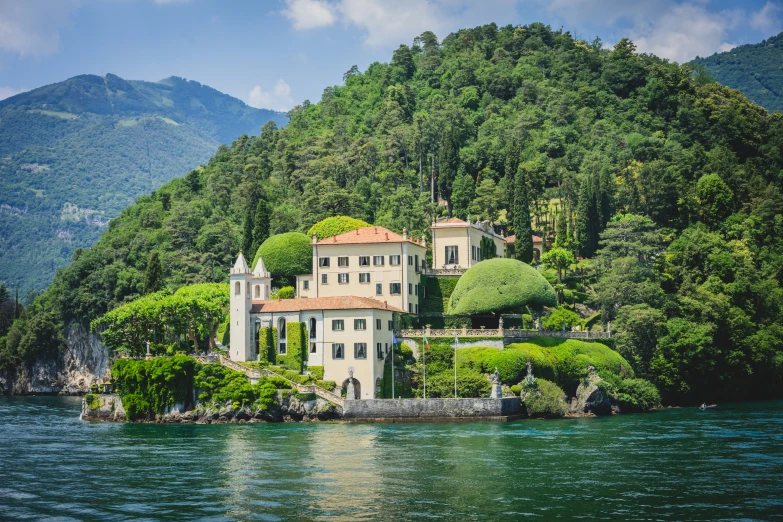 a house is sitting on an island surrounded by mountains