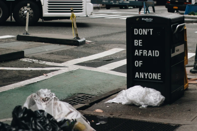 garbage bag sitting on the sidewalk by a post