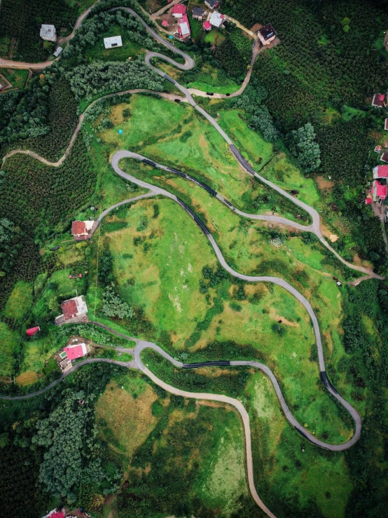 a winding road in the green countryside, is pographed from above