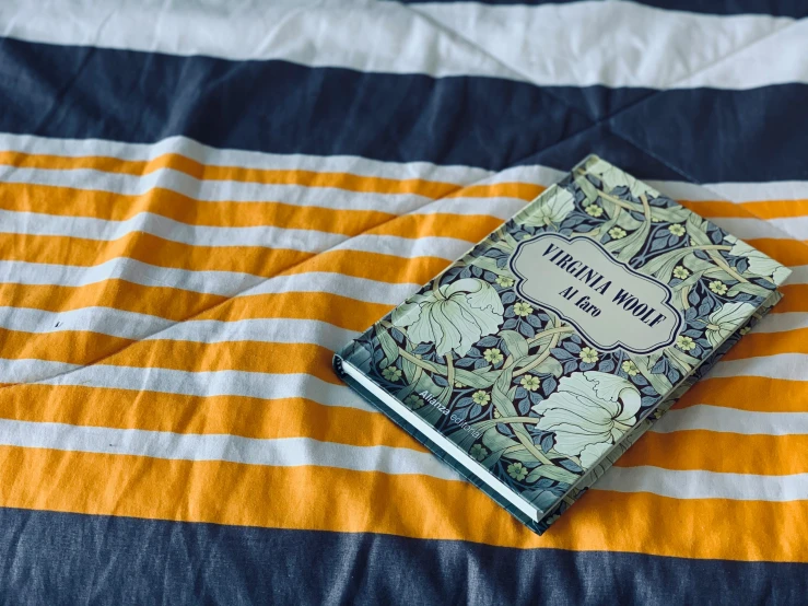 the small book is laying on a striped blanket